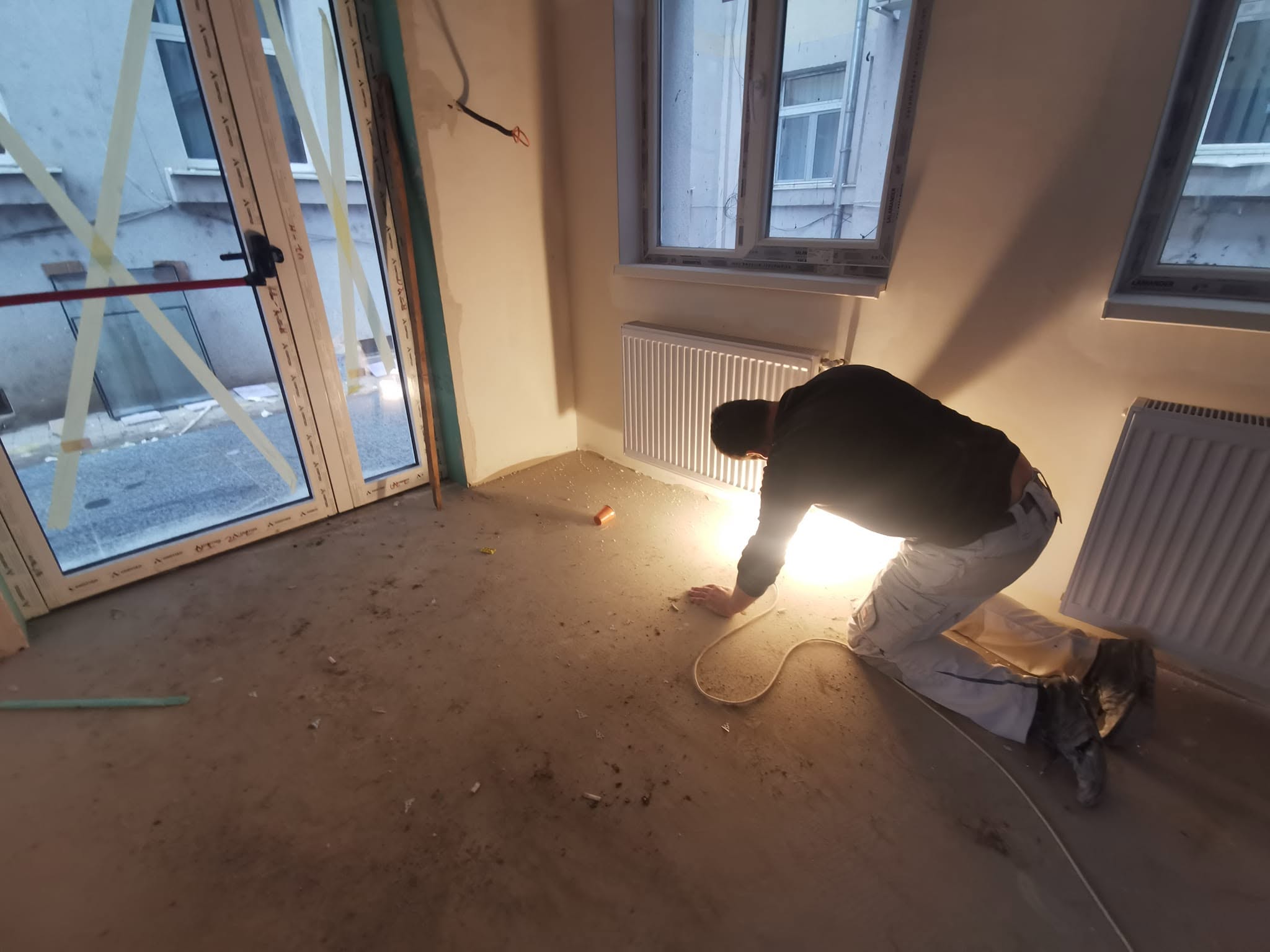 Tehnician Cover Instal lucrând la instalația termică într-o încăpere în renovare